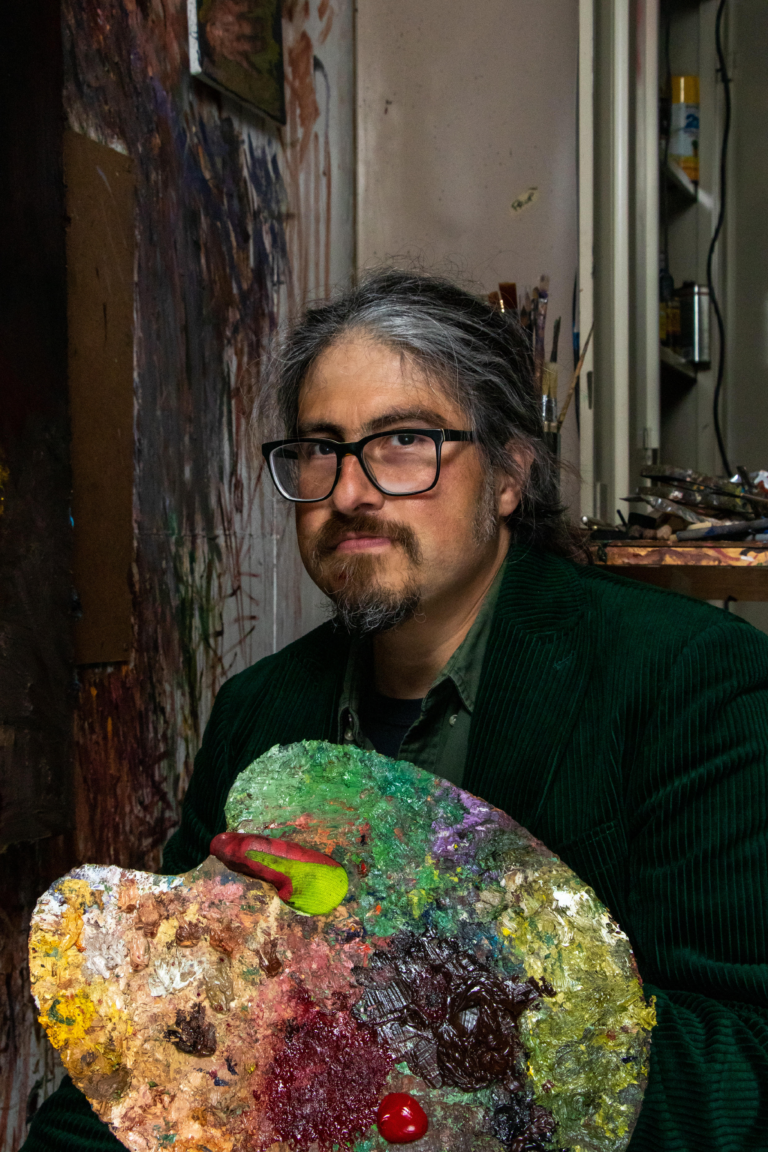 Artist Peter Daniel Bernal holds the paint palette he’s used for the last 15+ years