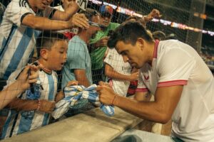 A soccer player signing a shirt for a child