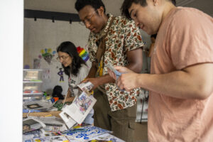 Isabella Mahuad (20), Jeff Childs (20), and Conner Whitt (22) find unity in diversity, assembling a newspaper collage at We the People-MI's event