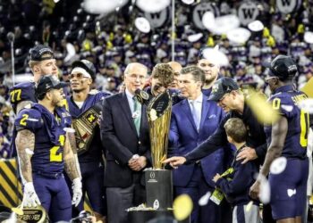 CFP president Bill Hancock, gets ready to present the CFP National Football trophy to the Wolverines after defeating the Huskies