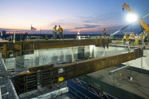 American and Canadian ironworkers shake hands upon placing the last major beam connecting the international boarder crossing on June 14, 2024