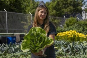 Dolores Perales, Co-director of Cadillac Urban Garden, stands with a freshly harvested bok choy.
