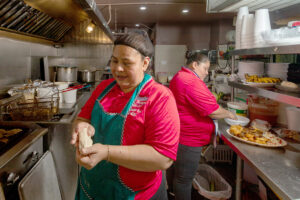 A la izquierda, Ana Vásquez de El Salvador prepara una pupusa. A la derecha, Maritza Serrano de Honduras finaliza un pedido de Yuca con Chicarrón. Según su estimación, preparan un promedio de 200 pupusas diarias.