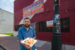 Ángel Trejo stands outside La Cuscatleca showcasing an order of Rice dough Pupusas con curtido. He helps his mother operate the market/ restaurant.