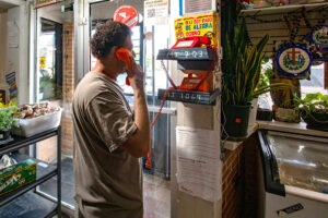 Gustavo M. envía dinero a su familia en El Salvador utilizando uno de los teléfonos exclusivos de la tienda.