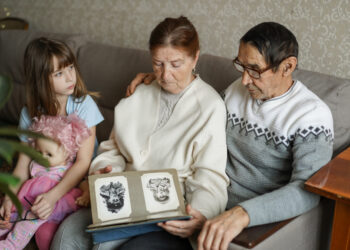 Illustration of a transnational migrant family going through a grieving process, with a loved one on a video call and another person holding a photo of a deceased family member, highlighting the emotional impact of migration challenges. Image concept by Juan Ochoa and created with DALL-E.