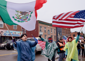 Daniel Mata, 18, left, waves a Mexican flag Tuesday, March 4 during a protest at Clark Park. Mata is a junior at Covenant High School Southwest. Photo by Dustin Blitchok/Planet Detroit