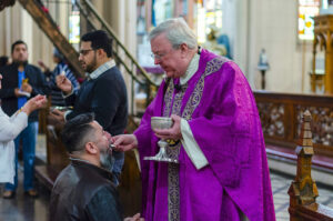 Msgr. Charles Kosanke, rector of the Basilica of Ste. Anne, offers Communion to a parishioner during a Mass at the basilica. Msgr. Kosanke announced the parish’s partnership with The Catholic Initiative during Masses the weekend of March 9. (Photo by Matthew Rich | Special to Detroit Catholic)