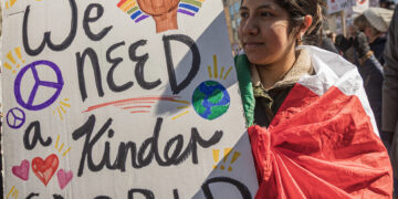 Protester holds a sign stating “We need a kinder world” at No Kings Demonstrations