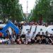 Team photo of all participants surrounding the FIRST Logo outside the main entrance to the competition