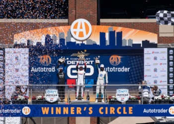 Alex Palou (Spain, #10) celebrates his first place victory at the 2026 Detroit Grand Prix alongside second place Kyle Kirkwood (USA, #27), and third place Graham Rahal (USA, #15) on top of the winners circl