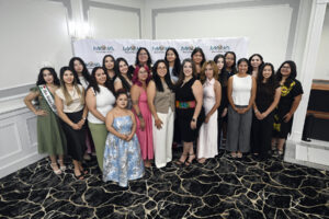 Large group of about 20 women posing together in front of a "MANA de Metro Detroit" step-and-repeat banner, one wearing a "Miss Mexico 2026" sash and tiara.
