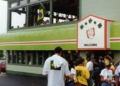 Exterior of a pub decorated with a Brazilian flag and a "Welcome" banner, with a crowd of soccer fans gathered outside and visible through an upstairs window.